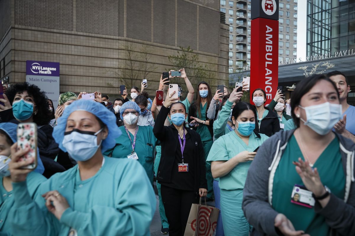 FILE - In this April 28, 2020, file photo Medical personnel attend a daily 7 p.m. applause in their honor, during the coronavirus pandemic outside NYU Langone Medical Center in the Manhattan borough of New York. Essential workers are lauded for their service and hailed as everyday heroes. But in most states nurses, first responders and frontline workers who get COVID-19 on the job have no guarantee they