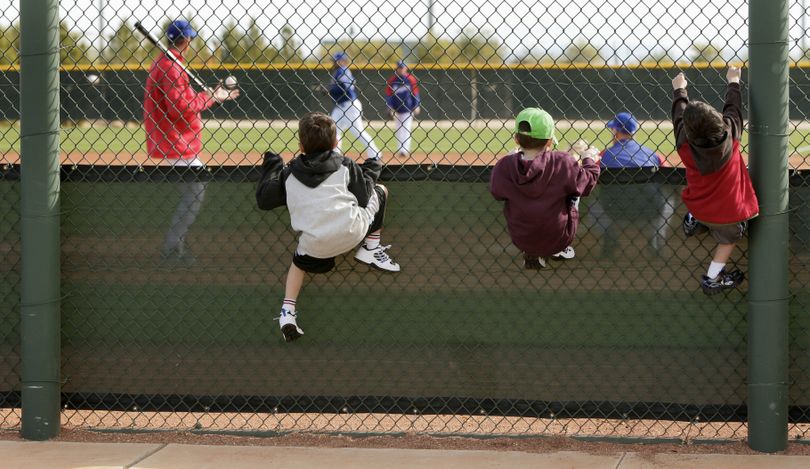 ORG XMIT: AZCR101 Cousins Matthew Justice, 6, from Oakland, Calif., left, Josh Rubinstein, 7, from Trumbull, Conn., center, Zach Justice, 4, from Oakland, Calif., hang on a fence to watch the Texas Rangers workout during baseball spring training Sunday, Feb. 15, 2009, in Surprise, Ariz. (AP Photo/Charlie Riedel) (Charlie Riedel / The Spokesman-Review)