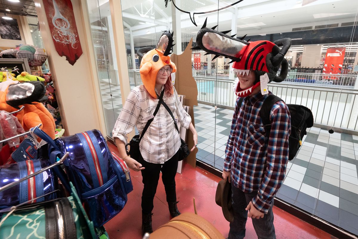 On a community outing, Elaina Nixon, left, a volunteer peer mentor with the TREK program and client Jackson VanHeel, 13, try on hats in the Comic Book Shop at NorthTown Mall on July 13. The Isaac Foundation runs the TREK program, which gives neurodivergent youths the opportunity to partner with peer-mentors and executive functioning coaches to learn the social skills needed to access their communities and demonstrate independence while navigating activities of daily living.  (COLIN MULVANY/THE SPOKESMAN-REVIEW)
