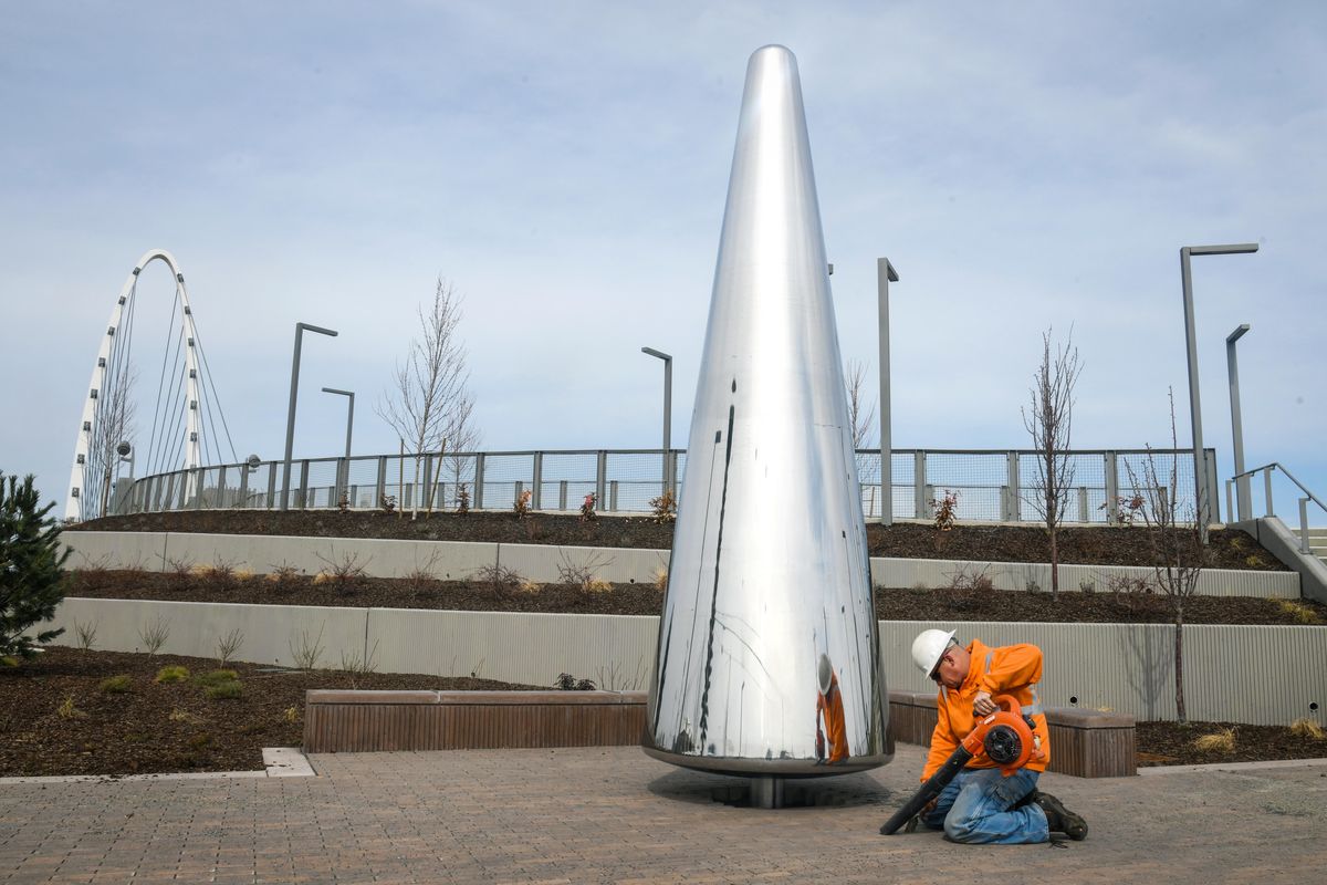 Greg Keller, of Garco Construction, clears debris from bricks to place a placard below the newly-installed “Soaring” art piece by artists Shani Marchant and the late Lea Anne Scott, Monday, March 25, 2019, on the south end of the University District Gateway Bridge. (Dan Pelle / The Spokesman-Review)