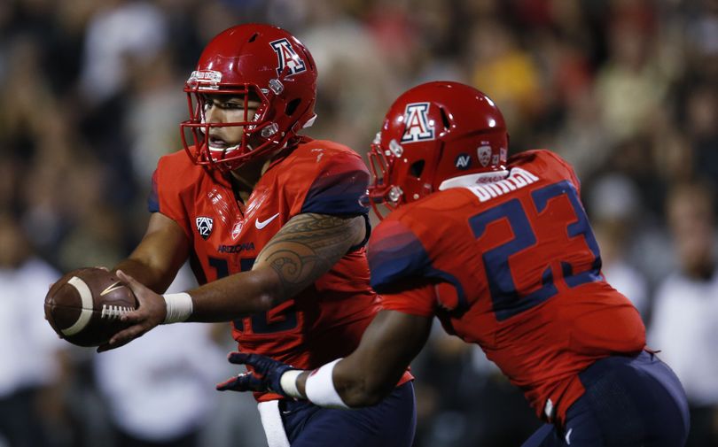 Arizona quarterback Anu Solomon, left, hands off the ball to running back Jared Baker for a long gain against Colorado in the first half of an NCAA college football game Saturday, Oct. 17, 2015, in Boulder, Colo. (David Zalubowski / Associated Press)