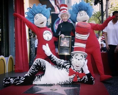 In this March 11, 2004 file photo, Audrey Geisel, widow of famed children’s book author Theodor Seuss Geisel, better known as Dr. Seuss, poses with The Cat in the Hat, foreground, and Thing 1 and Thing 2, who are characters from his books, at the dedication of Dr. Seuss’ posthumous star on the Hollywood Walk of Fame in Los Angeles. Geisel died peacefully at her La Jolla, Calif., home on Wednesday, Dec. 19, 2018, at age 97. (Reed Saxon / Associated Press)