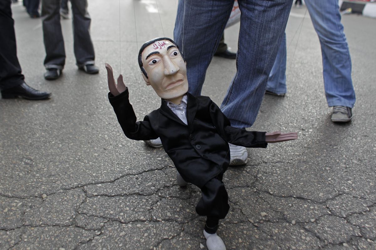 A puppet representing former Egyptian President Hosni Mubarak is walked by a man at Tahrir Square in Cairo, Egypt, on Friday. (Associated Press)