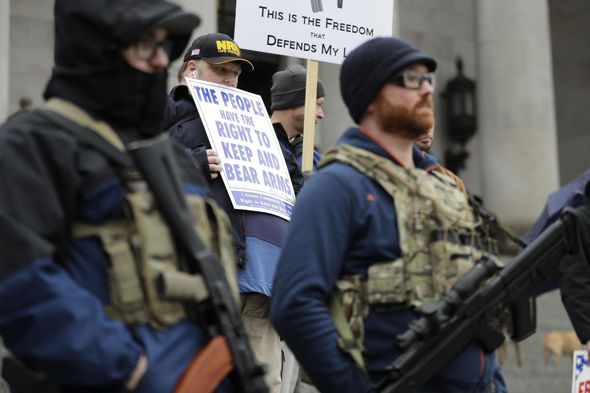 John Doll, second from left, of Renton, Wash., holds a sign that reads “The people have the right to bear arms” as he stands near people holding weapons at a gun rights rally, Friday, Jan. 12, 2018, at the Capitol in Olympia, Wash. The rally was organized by the Gun Rights Coalition group and was held to advocate and lobby for various gun and ammunition-related issues that will be addressed during the current 2018 legislative session. (Ted S. Warren / AP)