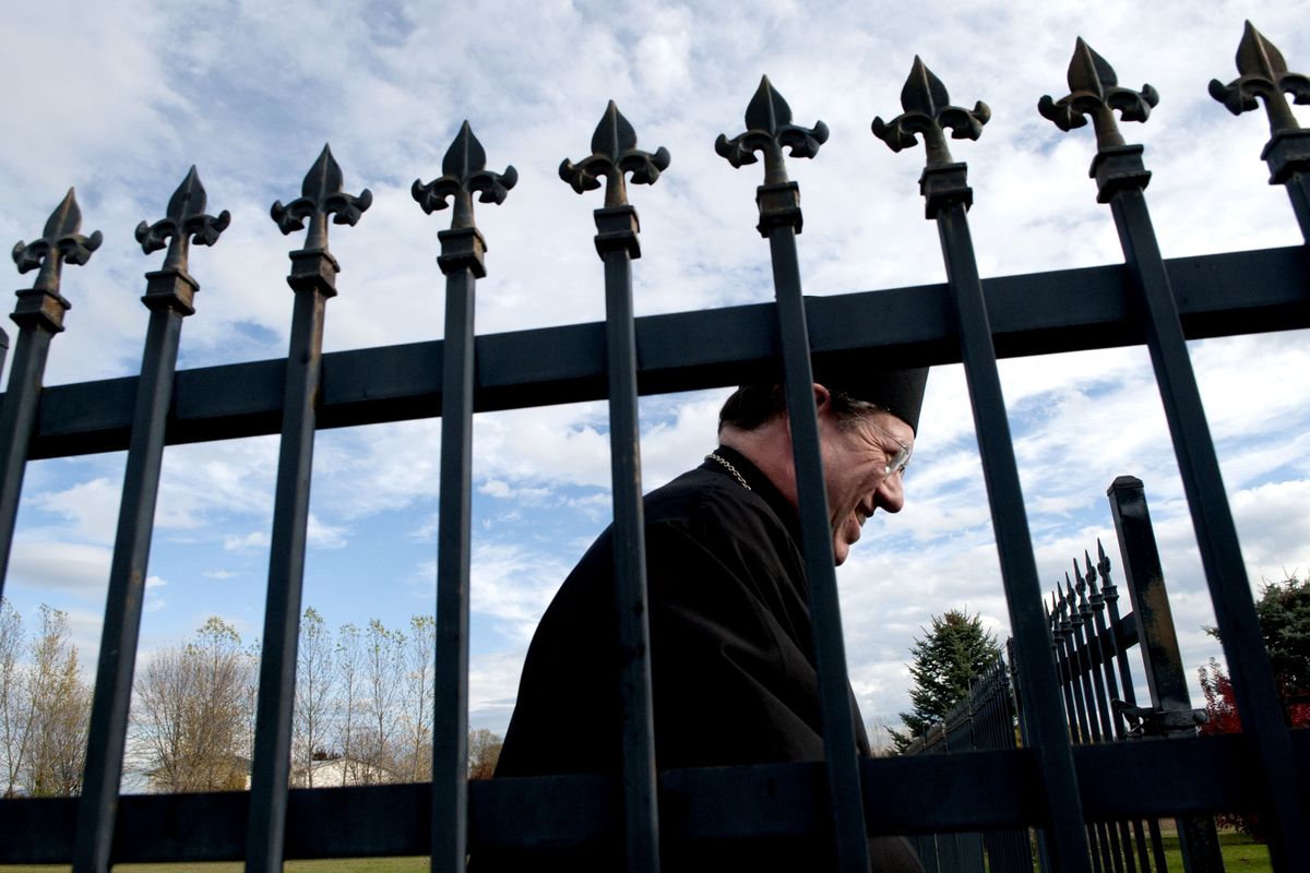 Father Basil, of St. John The Baptist Antiochian Orthodox Church, leads the way through the cemetery gates to the gravesite of war veteran Jim Ayers at the church in Post Falls on Thursday. (Kathy Plonka)