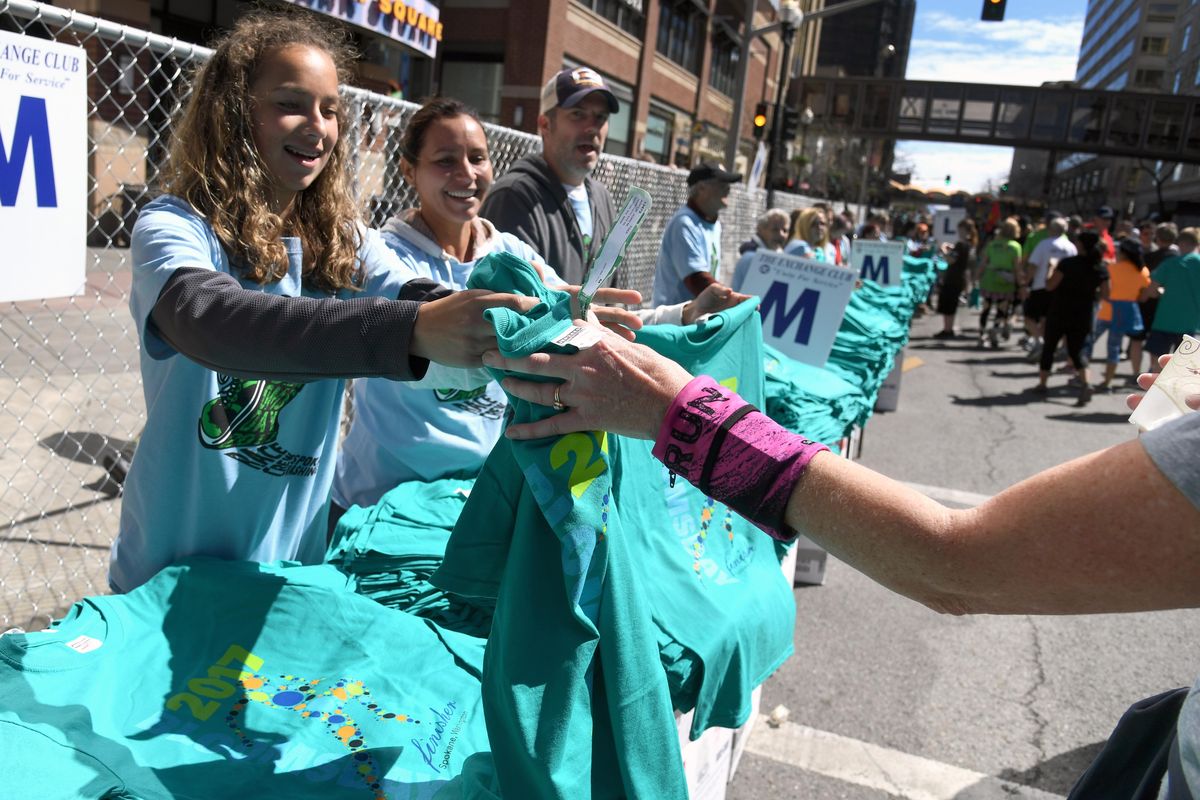 Kenzie Gaines, 15, and her mother Natalie hand out Bloomsday T-shirts to finishers on Main Avenue  during Bloomsday 2017, Sunday, May 7, 2017, in Spokane. (Colin Mulvany / The Spokesman-Review)