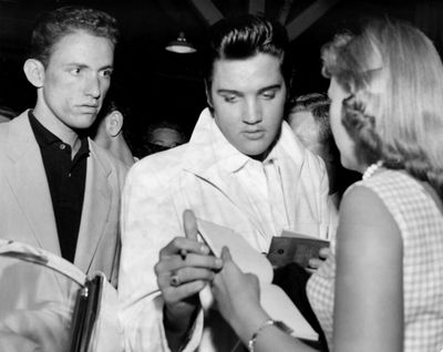 Elvis Presley is seen in Spokane in 1957, where he performed at Memorial Stadium. He traveled from Memphis by train, arriving on the Empire Builder. He signed autographs for a few of the 20 or so fans, including Jackie Stone, right, who were waiting at the station when he arrived.  (S-R PHOTO ARCHIVE)