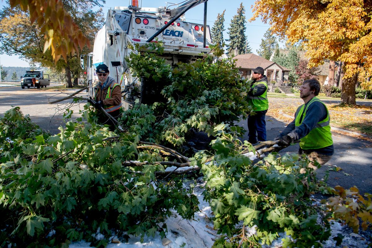 Spokane city employees pack fallen branches into a garbage truck on Spokane’s South Hill on Friday, Oct. 11, 2019, part of an all-out effort to clear debris from a snow storm that struck early Wednesday. (Jesse Tinsley / The Spokesman-Review)