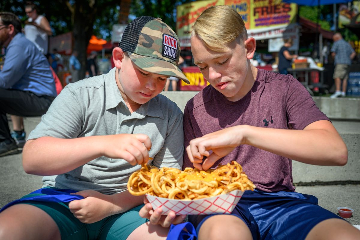 Brothers Oliver, Hampson 10, and Seth, 12, enjoy a “Block of Fries” during the opening day of Pig Out in the Park in this August 2019 photo.  (COLIN MULVANY)