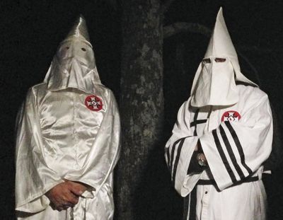 In this Friday, Dec. 2, 2016, photo, two masked Ku Klux Klansmen stand on a muddy dirt road during an interview near Pelham, N.C. (Jay Reeves / Associated Press)