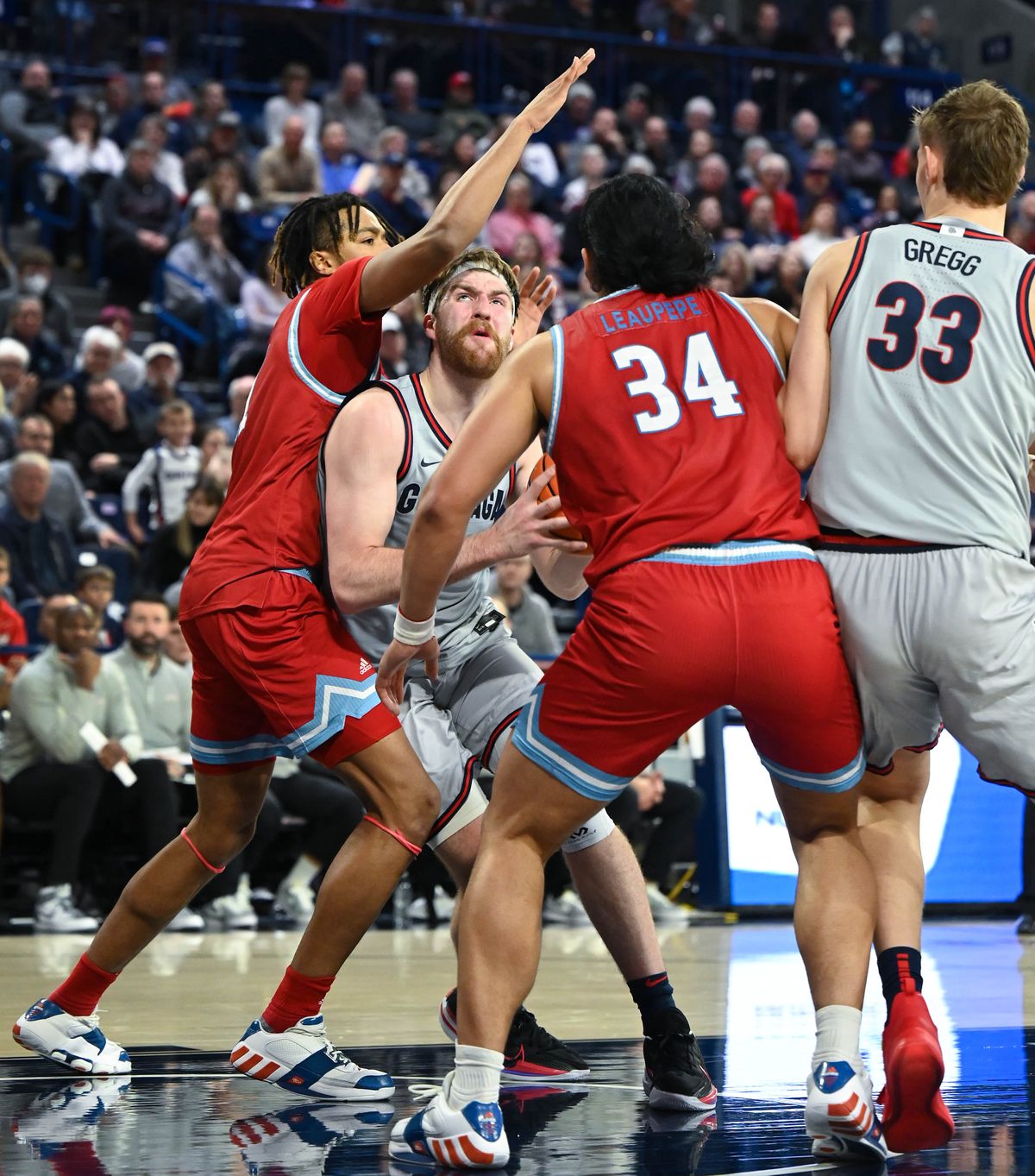 LMU’s Michael Graham, left, and Keli Leaupepe put the squeeze on Drew Timme’s drive into the lane.  (Colin Mulvany/The Spokesman-Review)