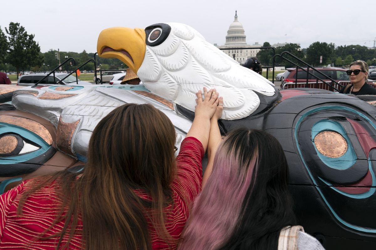 People touch a totem pole during a delivery ceremony by tribal leaders and Indigenous activists on Capitol Hill on Thursday in Washington, D.C.  (Jose Luis Magana/Associated Press)