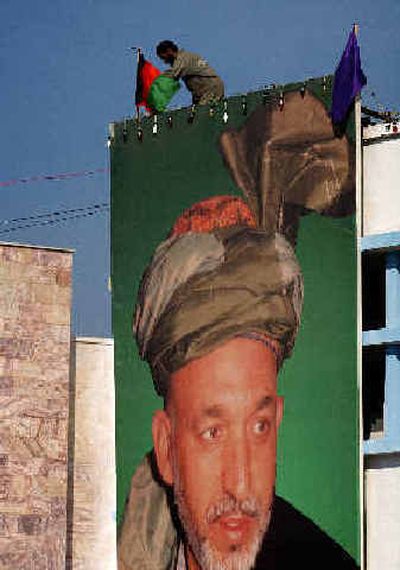 
A worker places an Afghan flag on a portrait of President Hamid Karzai in Kabul on Monday for the inauguration of the nation's first popularly elected president. 
 (Associated Press / The Spokesman-Review)