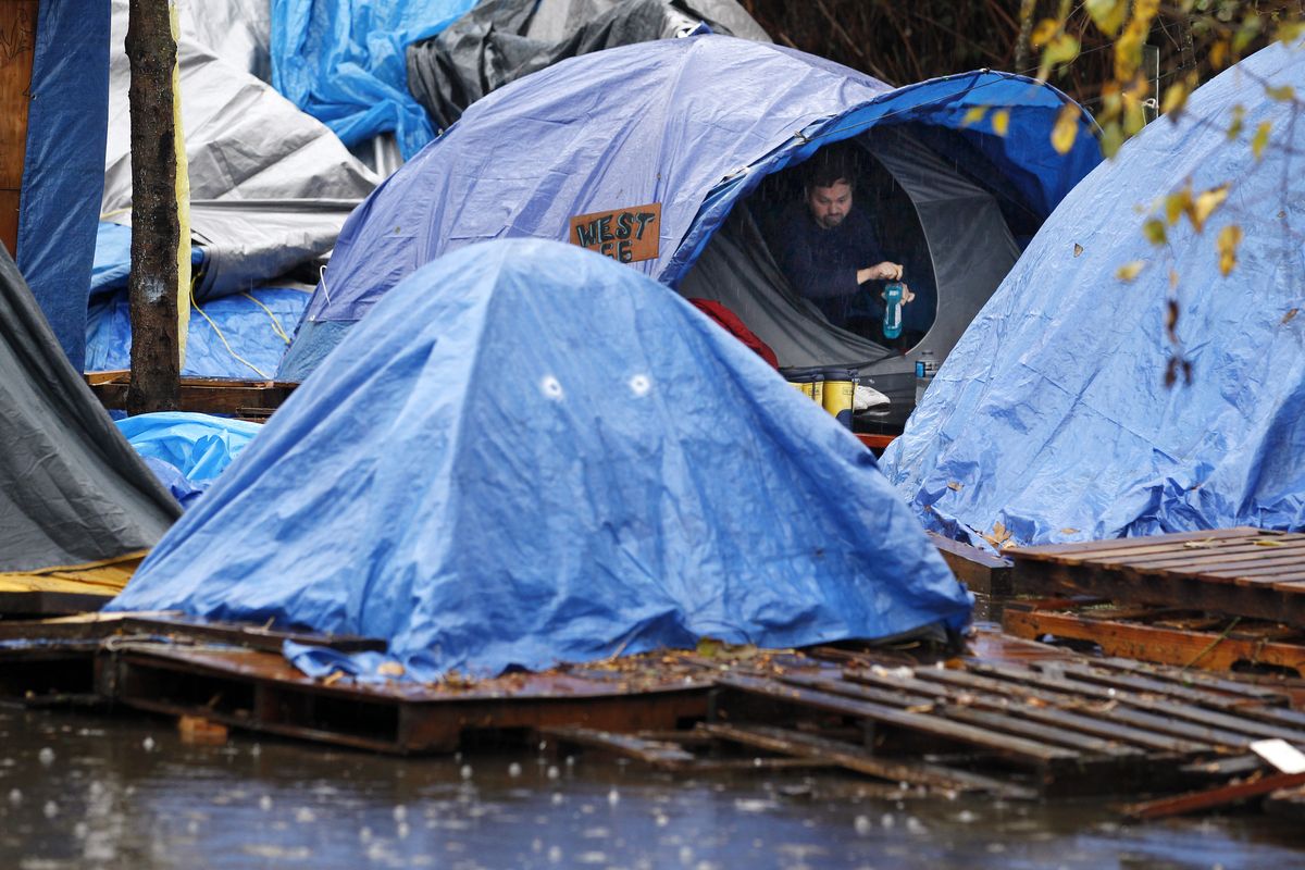 A resident looks out from a tent set atop wooden pallets in Nickelsville, a homeless encampment, where a day earlier a heavy rain and windstorm had partially flooded the camp in Seattle. A pump had drained much of the water by Tuesday. (Associated Press)