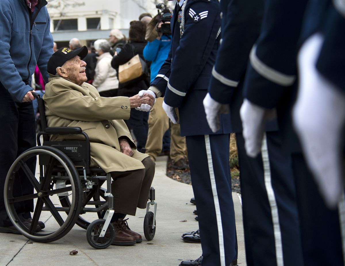 Pearl Harbor survivor George “Bud” Garvin shakes the hands of Fairchild Air Force honor guard members Sunday, after a ceremony at the Spokane Veterans Memorial Arena to commemorate the 73rd anniversary of the attack that began America’s involvement in World War II. (Dan Pelle)
