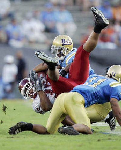 
Cougars running back DeMaundray Woolridge is tackled by a pair of Bruins. 
 (Associated Press / The Spokesman-Review)