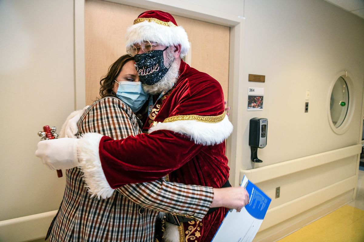 Providence Sacred Heart Hospital assistant manager for environmental services, Ed Kelly, playing Santa offers a hug to Katie Lowderback, NICU nurse manager and Family Support Services, in the hallway of Sacred Heart Children