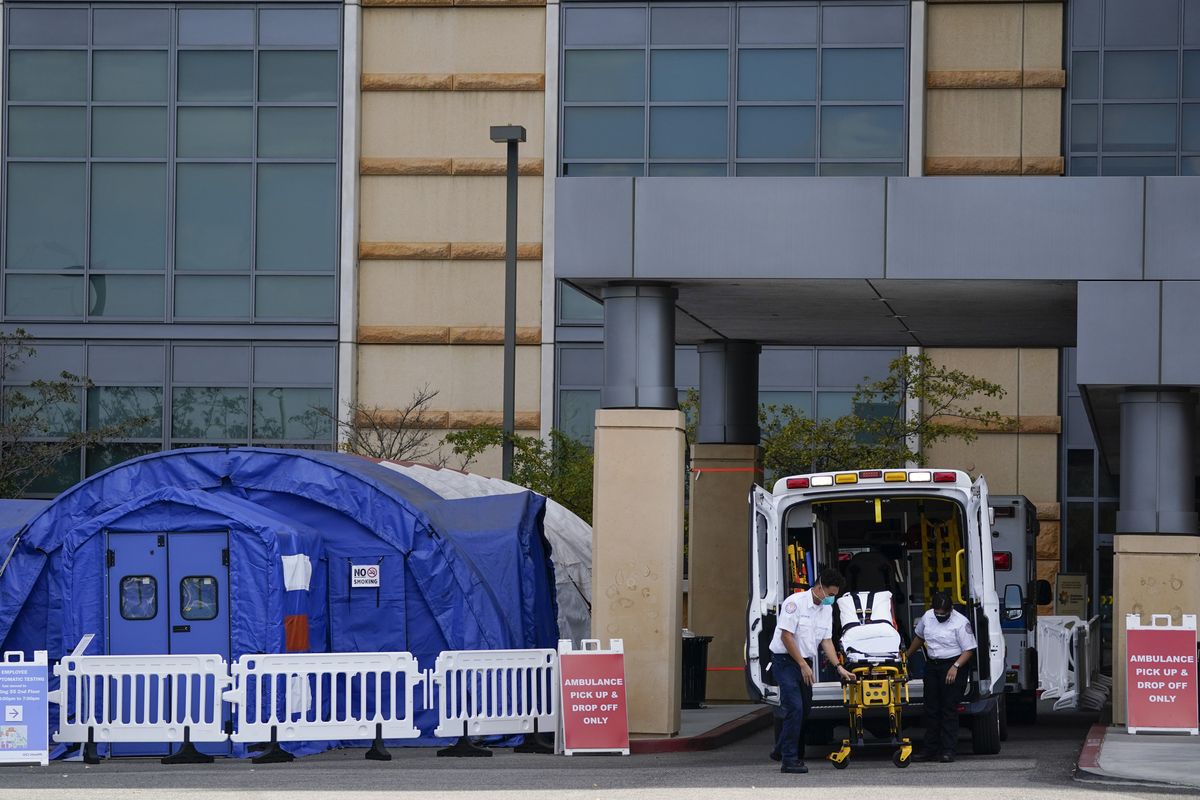 Medical workers remove a stretcher Dec. 17 from an ambulance near medical tents outside the emergency room at UCI Medical Center in Irvine, Calif. COVID-19 deaths in the state have surpassed the 25,000 mark.  (Ashley Landis)