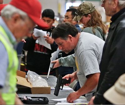 Prospective buyers preview guns at a February auction of inventory from the closed Kesselring Gun Shop in Burlington, Wash. The store was a fixture in the Northwest for more than 65 years before surrendering its federal firearms license in October. (Mark Harrison)