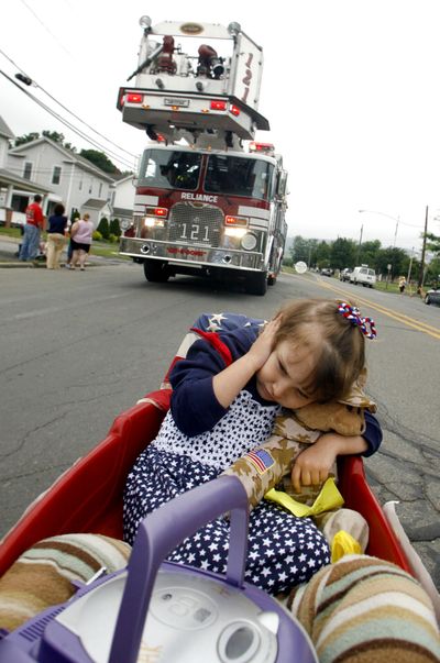 ORG XMIT: PABLO101 Halo Kaiser, 3, blocks her ears with her hand and a teddy bear while being pulled along in her wagon as the siren from the Reliance Fire Company's aerial platform blares while taking part in the Berwick Elks Pet and Toy Parade in Berwick, Pa., Thursday, June 11, 2009. (AP Photo/Bloomsburg Press Enterprise, Jimmy May) (Jimmy May / The Spokesman-Review)