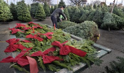 Lot manager Torrey Sprenger, background, helps Nick Page select a tree at the Spokane Boys lot at 44th and Regal on Dec. 3 in Spokane.  (CHRISTOPHER ANDERSON / The Spokesman-Review)