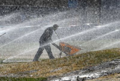 
Jeremy Leech of Hidden Rivers Irrigation & Landscaping makes his way through streams of sprinkler water as he and others continue work around the new Ferris High School gym on Thursday. New sod had just been placed and needed to be watered. 
 (Dan Pelle / The Spokesman-Review)