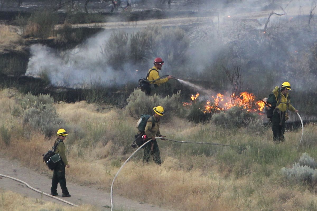 FILE - In this June 30, 2016 file photo firefighters respond to a wildfire near the Morningside Heights neighborhood near Table Rock in east Boise, Idaho. With a potential ferocious wildfire season ready to ignite across the western U.S., the push is on to persuade state and federal wildland firefighters to get vaccinated against COVID-19. Republican Idaho Gov. Brad Little said Tuesday, May 18, 2021, that lives could be lost if frontline firefighters get sidelined with the illness.  (Joe Jaszewski)