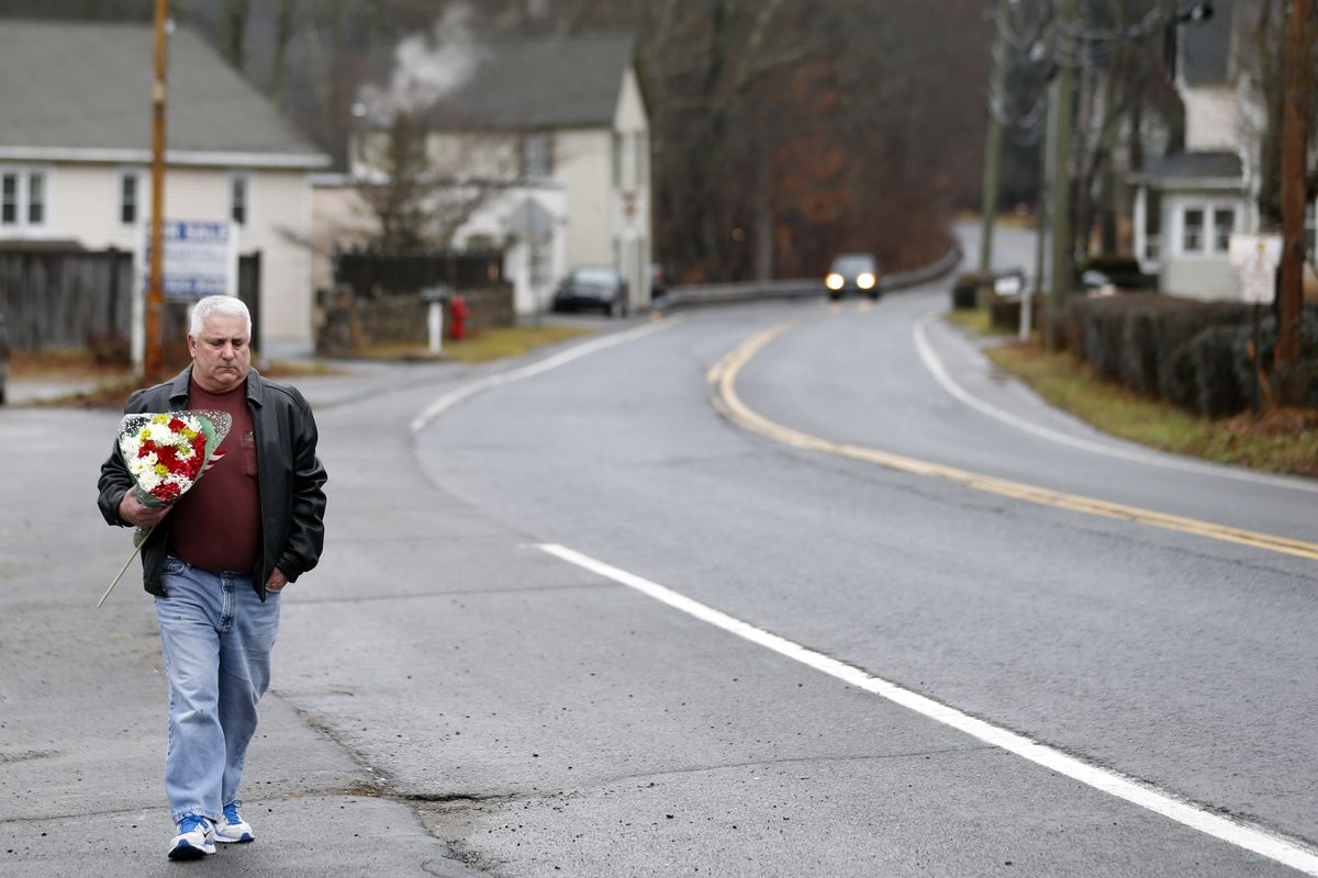 A man walks with flowers in the Sandy Hook village of Newtown, Conn., as the town mourns victims killed in a school shooting, Monday, Dec. 17, 2012. Authorities say a gunman killed his mother at their home and then opened fire inside the Sandy Hook Elementary School in Newtown, killing 26 people, including 20 children, before taking his own life, on Friday. (Julio Cortez / Associated Press)