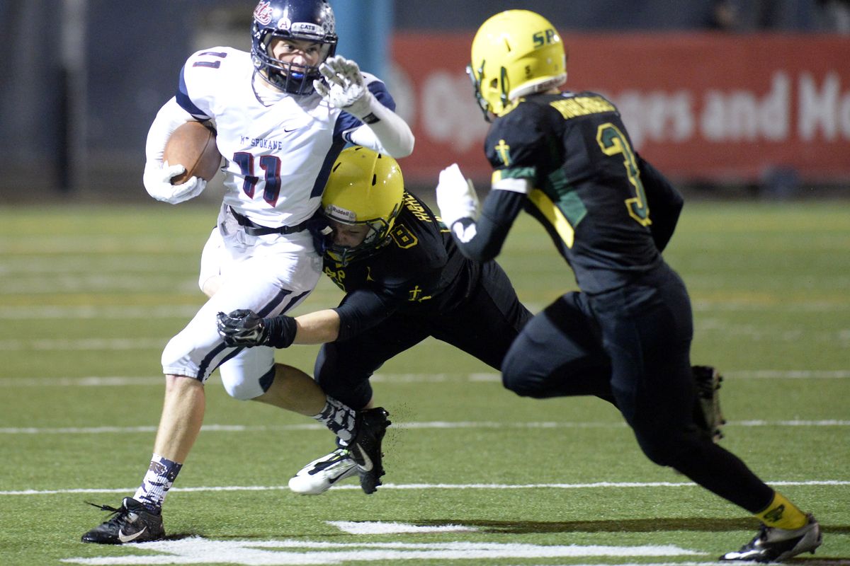 Mt. Spokane’s Bryce Zimmerer takes a short pass and tries to elude Shadle Park defenders Jake Stevens and T.J. Trout, right. (Jesse Tinsley)