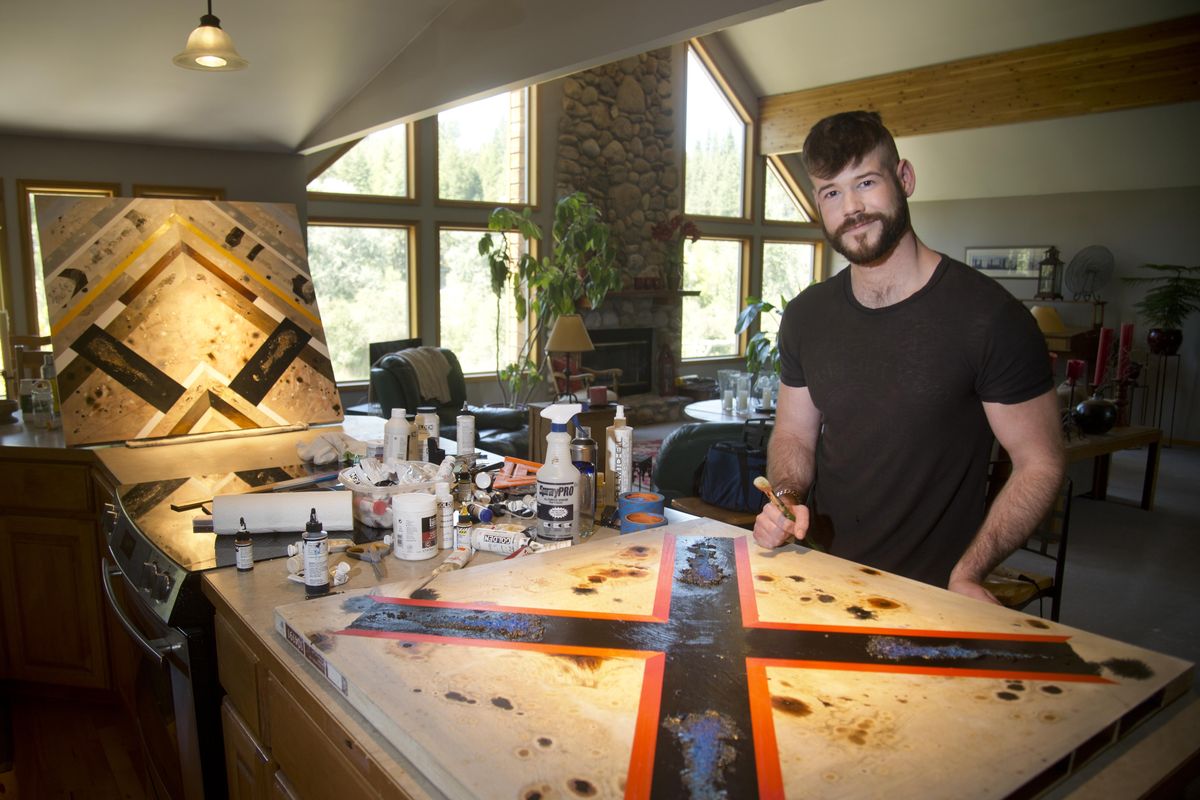 Artist Matthew Schwenk stands at his kitchen counter, where he often works on his paintings – mostly abstract designs that will eventually be covered with a thick layer of shiny resin. (Jesse Tinsley / The Spokesman-Review)