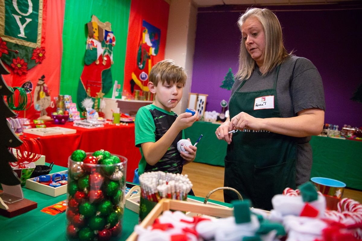 Cash Marley, 8, consults with "elf" helper Renea at the Santa Express shop on the second floor of River Park Square on Tuesday, Dec. 11, 2018. The Santa Express is in its 26th year and is completely run by volunteers, and 100 percent of proceeds benefit the Vanessa Behan Crisis Nursery. (Libby Kamrowski / The Spokesman-Review)
