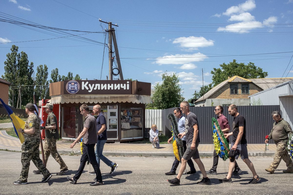 A villager kneels on the ground as a tribute to fallen Ukrainian soldier Anatoly Mykolayovych Potaychuk, 40, as his casket is taken to the cemetery for burial on Saturday, July 2, 2022, in the small village of Babyntsi, Ukraine. The Russian and Ukrainian armies have both been badly mauled, raising questions about how long they can keep fighting as they have, particularly the outgunned Ukrainians. (Mauricio Lima/The New York Times)  (MAURICIO LIMA)