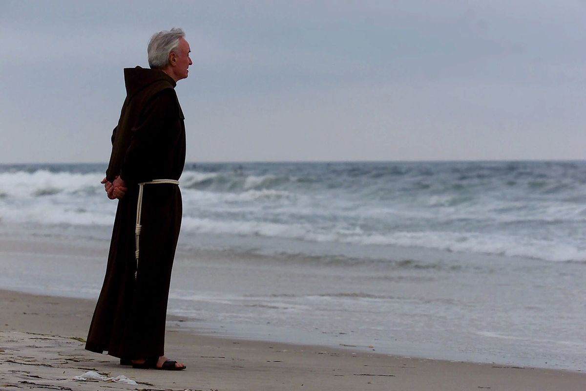 In this July 17, 2000 photo, Father Mychal Judge, a chaplain with the New York City Fire Department, stands at the shore before a service where 230 candles were lit for the July 17, 1996 victims of TWA Flight 800, at Smith Point Park in Shirley, N.Y. Judge left a uniquely complex legacy that continues to evolve 20 years after his death.  (Ed Betz)
