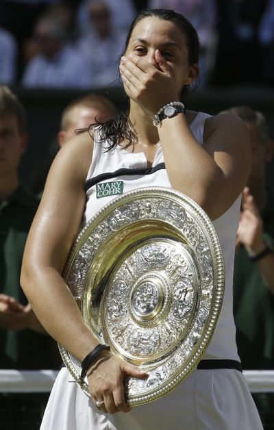 Marion Bartoli of France holds the trophy after winning the women’s singles final. (Associated Press)