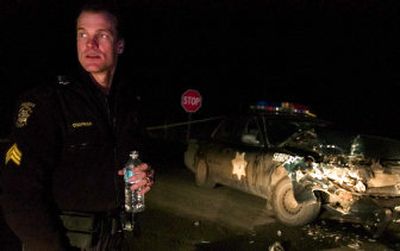 
Whitman County Sheriff's Sgt. Chris Chapman stands near the wreckage of his patrol car on the Washington and Idaho border near Tekoa, Wash., on Thursday night. Chapman was rammed by a stolen Spokane Valley Fire Department medic vehicle that police had chased for miles at speeds up to 90 mph. 
 (Kathryn Stevens / The Spokesman-Review)