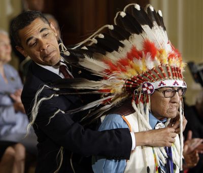 President Barack Obama reaches around the headdress of Chief Joseph Medicine Crow to place a 2009 Presidential Medal of Freedom around his neck during a ceremony Aug. 12, 2009, in the East Room of the White House. (Alex Brandon / Associated Press)