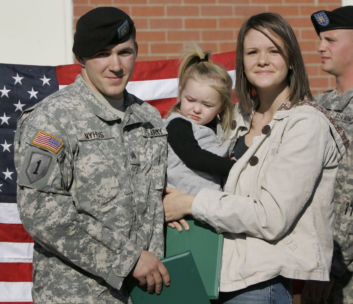Sgt. Ryan Nyhus poses with his wife, Ashley, right, and daughter, Caidence, following a re-enlistment ceremony at Fort Riley, Kan. (Associated Press / The Spokesman-Review)
