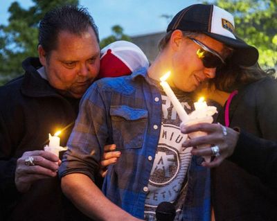 Cody Fowler, center, who grew up with Leo C. Neal for many years, is hugged by Leo Neal Sr, left, and Misty Neal during a candlelight vigil held Wednesday night at Post Falls High School. (Loren Benoit/Coeur d'Alene Press photo)