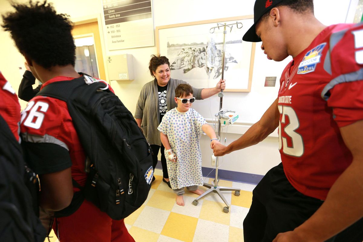 Trent Larson greets Washington State’s Nnamdi Oguayo, right, during the Cougars’ visit to El Paso Children’s Hospital on Thursday.