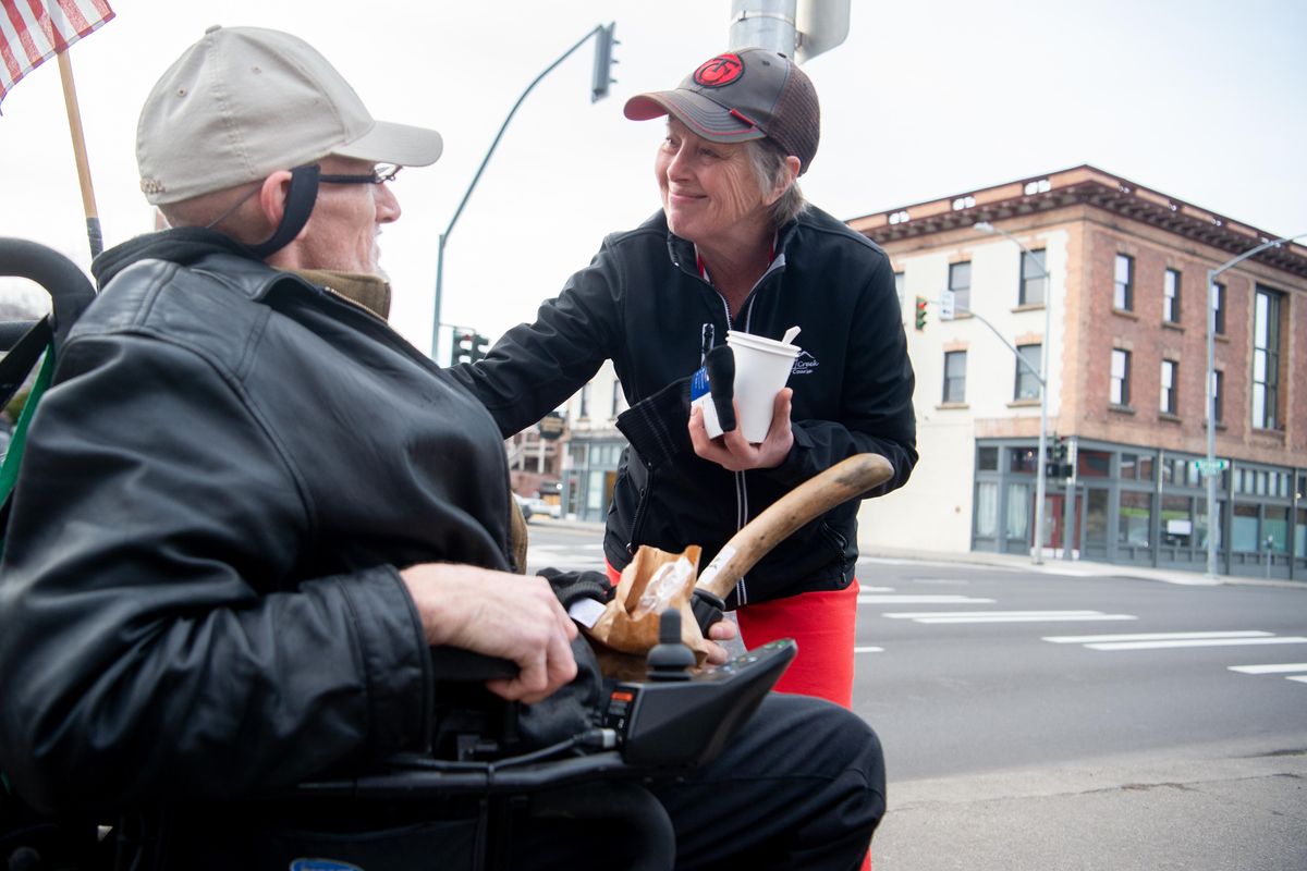 Deb Maier shares a moment with a man in a wheelchair with the street name “Ozone”, who came by while Maier and her husband Brad were out serving soup, sandwiches and coffee near Browne St. and Sprague Ave., Friday, Jan. 4, 2018. Maier and her husband set up a small table with a large pot of homemade soup and offered people food, pairs of socks and whatever else they could. Ozone said he liked Maier’s hat and she traded hats with him. (Jesse Tinsley / The Spokesman-Review)