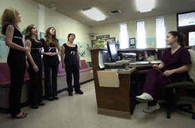 Receptionist Heather Crabb, far right, listens as Meisha Hemenway, 16, far left, Kali Clark, 15, Anna Daines, 15, and Alex Mackey, 15, sing 