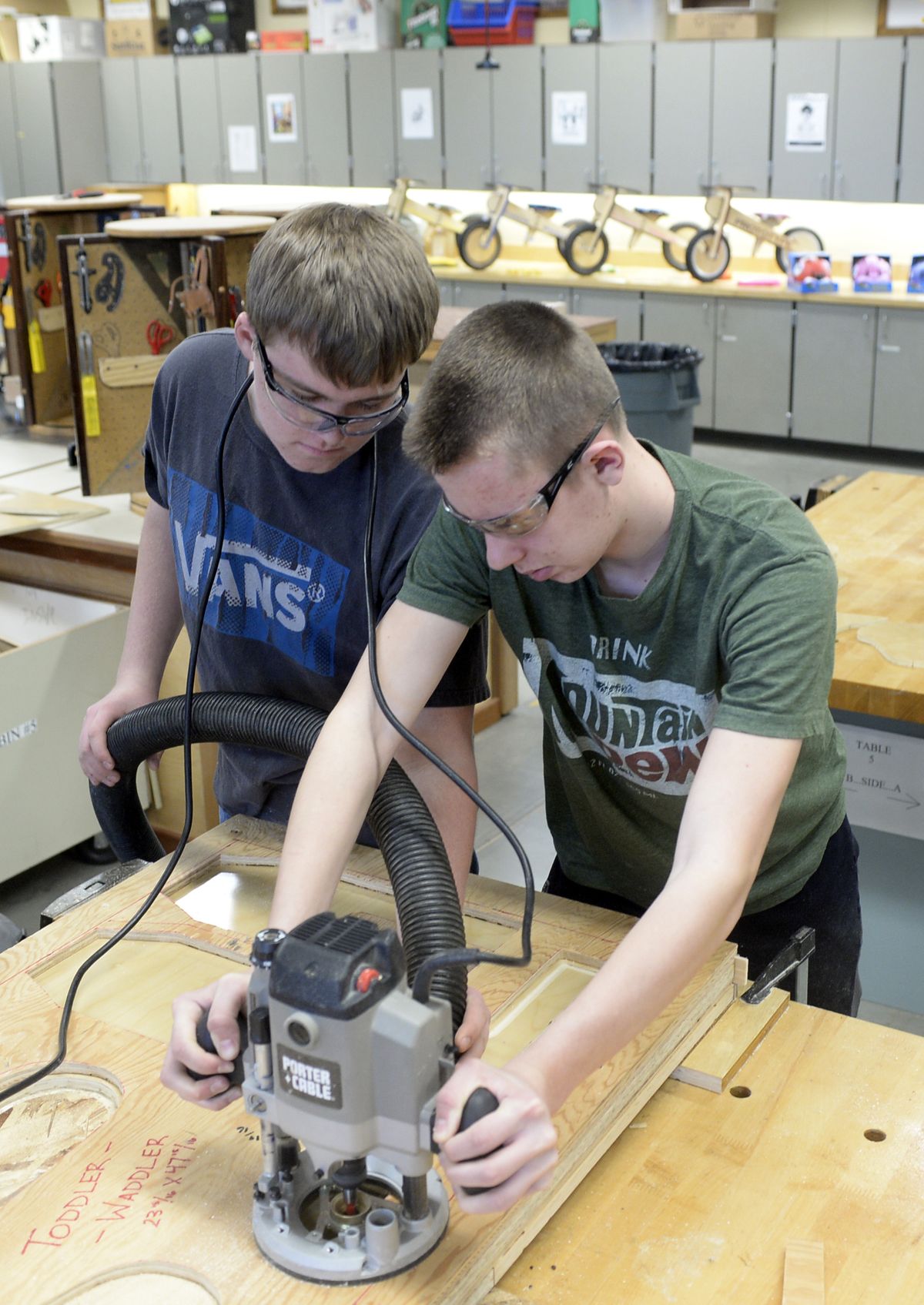 In the shop at Shadle Park High School, Tyler Niles, left, and Coty Melville use a router to cut out parts for a toddler bike Monday. The bikes are for sale and the kids in the program are donating some to the Child Development Program at the school. (Jesse Tinsley)