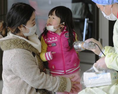A mother and daughter receive radiation exposure scanning in Fukushima, northern Japan, today. Low levels of radiation have been detected well beyond Tokyo, which is 140 miles south of the damaged nuclear plant, but hazardous levels have been limited to the plant itself. (Associated Press)