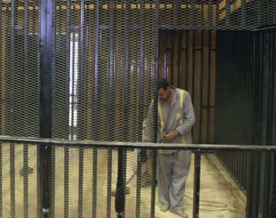 An Egyptian worker sweeps the cage in a courtroom at the national police academy in a Cairo suburb Sunday. Ousted President Hosni Mubarak, his security chief and two sons are scheduled to stand trial there Wednesday. (Associated Press)
