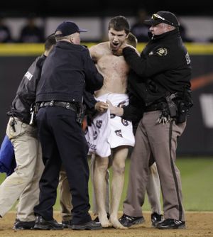 A fan is brought to his feet by police after being tackled while running naked onto the field during the baseball game between the Seattle Mariners and New York Yankees Saturday, May 28, 2011, in Seattle. The fan, who was arrested, was the third of four fans who ran onto the field at different times during the game. (Elaine Thompson / Associated Press)