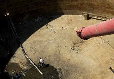 
A worker stands at the bottom of the nearly empty ruptured tank that killed a worker and dumped tons of raw sewage at the sewage plant in Spokane. 
 (Brian Plonka / The Spokesman-Review)