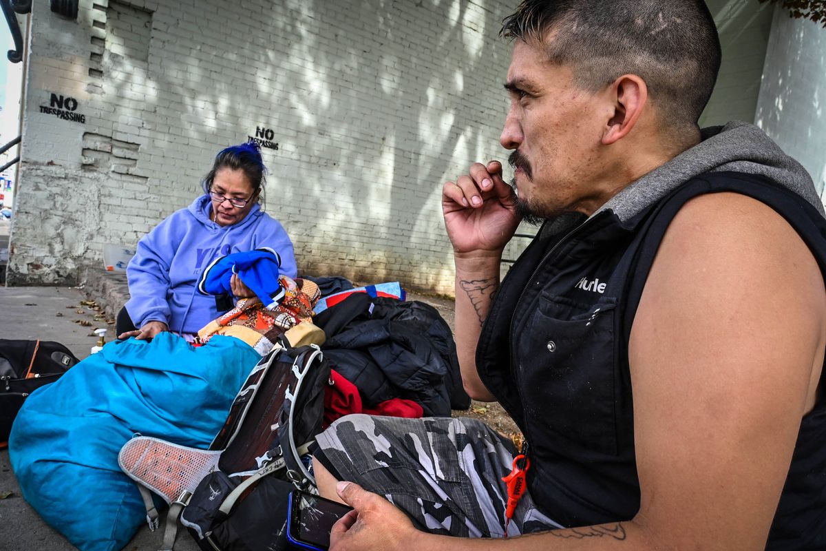 Rita and Michael Sherwood sit near the curb with their belongings outside their apartment on Wall Street and Third Avenue., Tuesday, Sept. 12, 2023, in Spokane. The building is deemed uninhabitable.  (DAN PELLE/THE SPOKESMAN-REVIEW)
