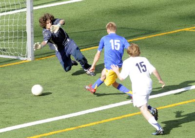 Erik Hansen of Mead, center, taps the ball past Central Valley goalkeeper Ryan Wurz for the game’s only goal as Bears defender Foster Newberg trails.  (Jesse Tinsley / The Spokesman-Review)