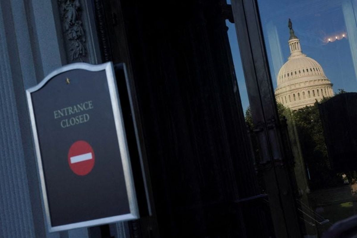 The U.S. Capitol dome is reflected in the Library of Congress glass door, with the sign reading "Entrance closed" in the foreground, on the first day of a partial government shutdown in Washington, D.C., U.S., October 1, 2025. REUTERS/Nathan Howard  (Nathan Howard)