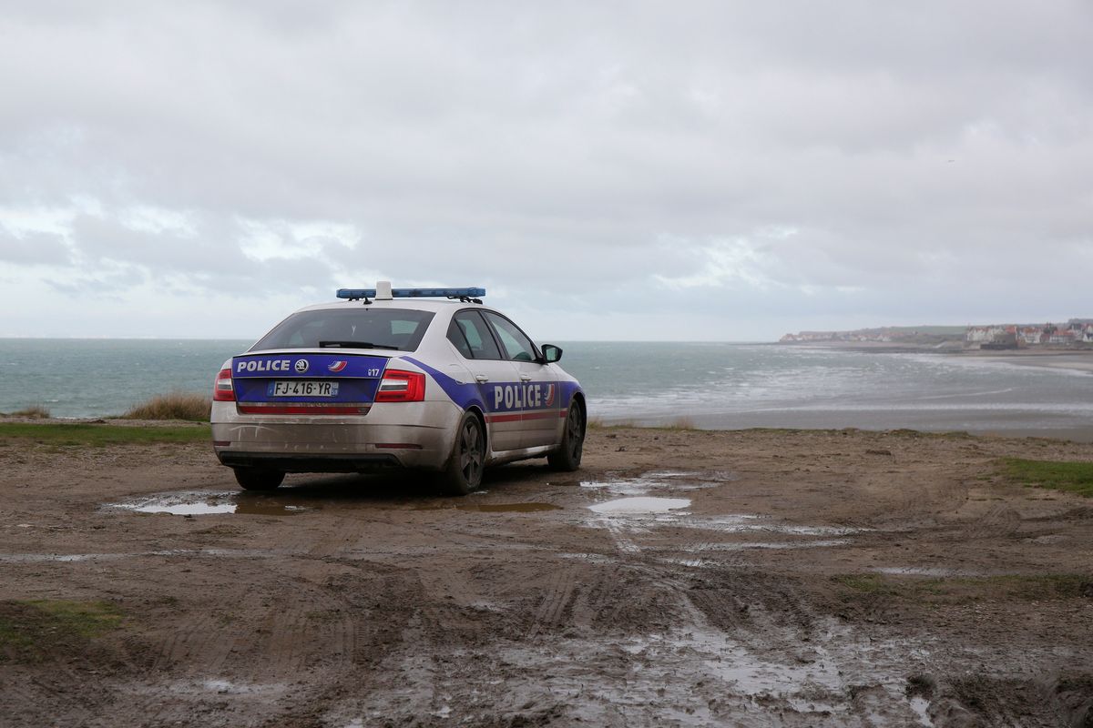 FILE- A police car parks over the shore in Wimereux, northern France, Thursday, Nov. 25, 2021 in Calais, northern France. The price to cross the English Channel varies according to the network of smugglers, between 3,000 and 7,000 euros. Often, the fee also includes a very short-term tent rental in the windy dunes of northern France and food cooked over fires that sputter in the rain that falls for more than half the month of November in the Calais region.  (Michel Spingler)